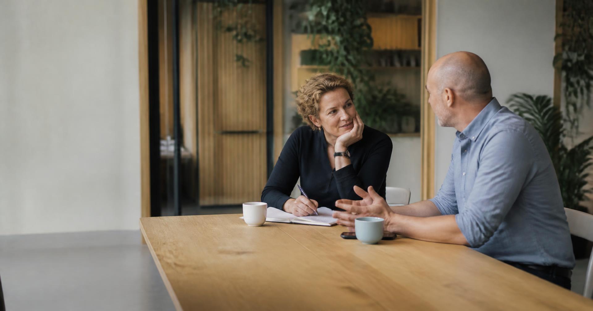 Two Agile professionals in conversation at a table in a bright office